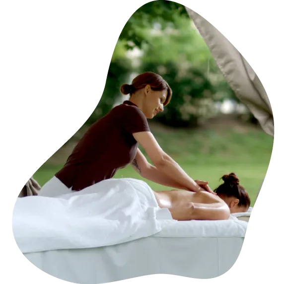 Ženska v črni športni majici masira žensko v beli brisači na masažni mizi