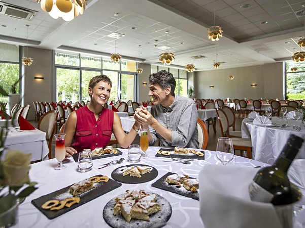 Moški in ženska sedita za polno mizo dobrot v hotelski restavraciji in se pogovarjata