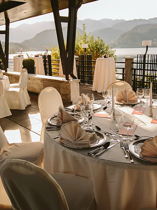 Lepo urejena terasa hotelske restavracije ob Blejskem jezeru s pripravljenimi mizami in stoli