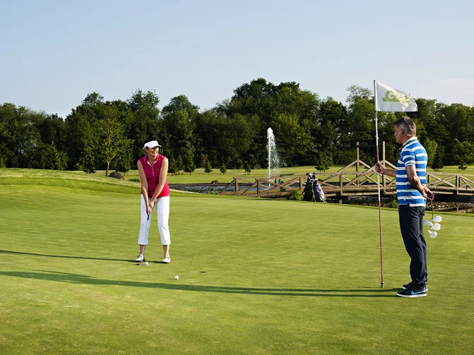 Moški in ženska v športnih oblačilih igrata golf na golf igrišču