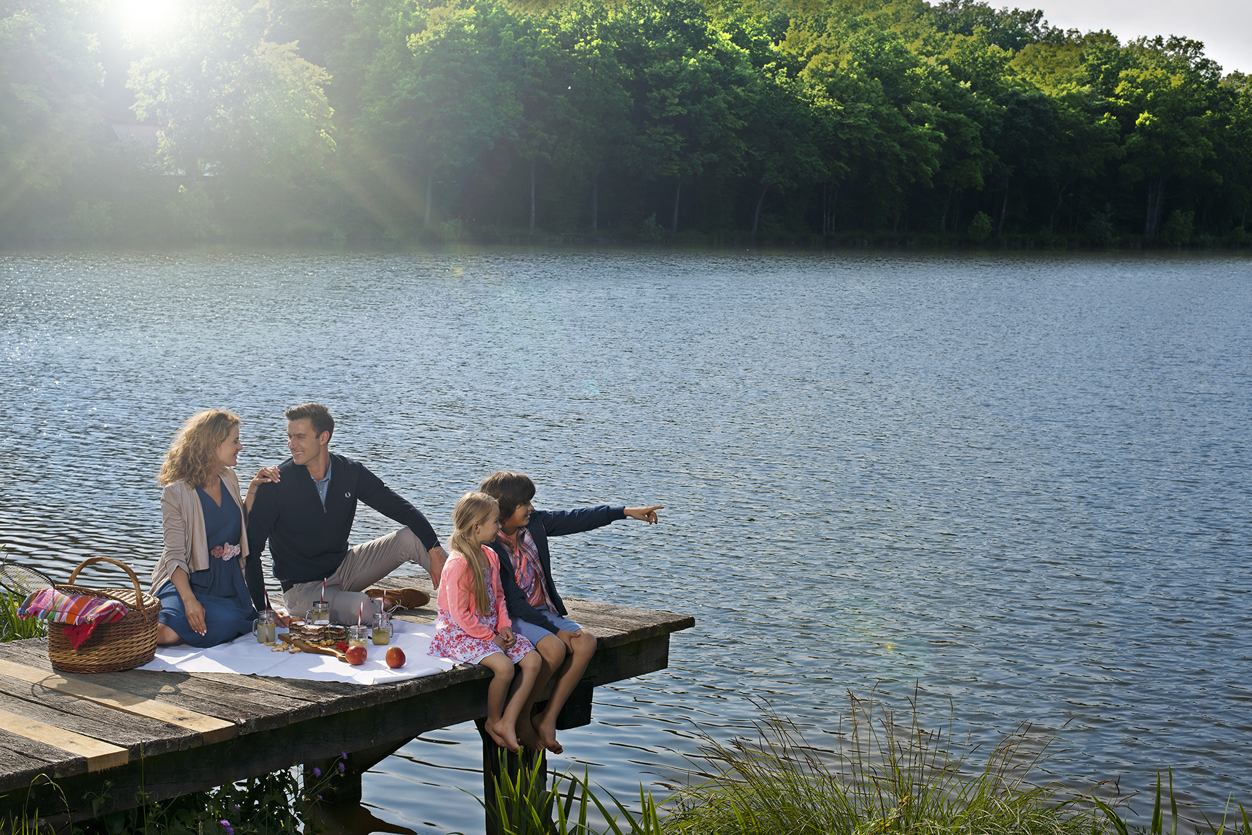 Štiričlanska družina ima piknik na leseni razgledni ploščadi ob jezeru