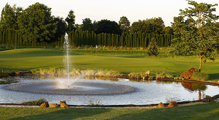 Pogled na sproščujočo vodno fontano ob zelenem golf igrišču