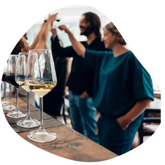 Skupina ljudi nazdravlja s kozarcem vina v roki