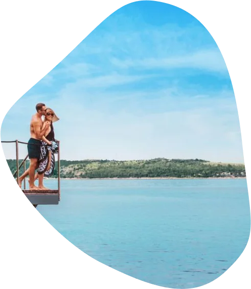 Moški in ženska se v kopalkah objemata na terasi s pogledom na morje
