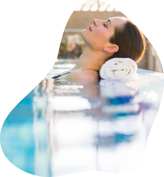 Ženska z brisačo pod glavo sproščeno počiva v bazenu
