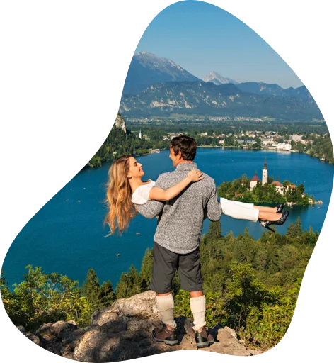 Moški drži žensko v naročju na razgledni točki v okolici blejskega jezera